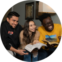 Three students sit on a couch having a bible study.